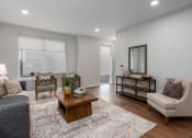 Thumbnail 13 of 71 - living room with rich plank flooring, oversized windows with custom shades, full size sofa, two arm chairs, coffee table and end table at The Flats & Terraces at Wildhorse Village, Chesterfield, MO 63