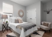 Thumbnail 17 of 71 - 2nd bedroom with rich plank flooring, oversized window with custom shade, full size bed with nightstand and arm chair at The Flats & Terraces at Wildhorse Village, Chesterfield