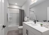 Thumbnail 20 of 71 - 2nd bathroom with tub, white quartz vanity, modern white cabinetry, matte black finishes and large mirror at The Flats & Terraces at Wildhorse Village, Chesterfield Missouri