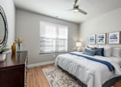 Thumbnail 14 of 18 - A bedroom with a bed, a dresser, a ceiling fan, and a window with blinds.
