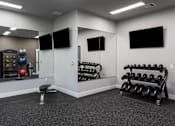 Thumbnail 4 of 18 - A gym room with a mirror, weights, and exercise equipment.