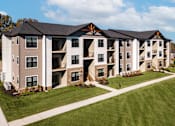 Thumbnail 2 of 18 - A large apartment complex with multiple balconies and a well-maintained lawn.