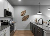 Thumbnail 12 of 18 - A modern kitchen with a black stove top oven and white cabinets.
