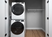 Thumbnail 10 of 18 - A white dryer is stacked on top of a white washer in a small laundry room.