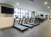 Thumbnail 14 of 22 - A gym with treadmills and a television on the wall.