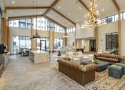 Thumbnail 3 of 22 - A large, well-lit living room with a variety of seating options and a chandelier.