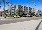 Thumbnail 5 of 5 - A yellow car is parked on the side of the road in front of a building.