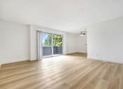 Thumbnail 1 of 12 - A room with wooden flooring and a sliding glass door leading to a balcony.