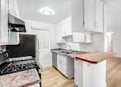 Thumbnail 3 of 12 - A kitchen with a black stove top oven and white cabinets.