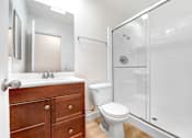 Thumbnail 6 of 12 - A white toilet sits in a bathroom next to a sink and a shower.