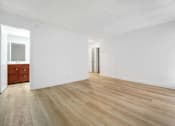 Thumbnail 8 of 12 - A room with wooden flooring and white walls.