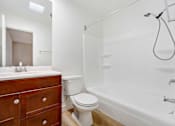 Thumbnail 9 of 12 - A white bathroom with a wooden vanity and a white toilet.