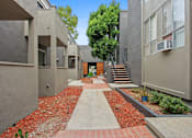 Thumbnail 11 of 12 - A pathway with red bricks leads to a building with a brown door.