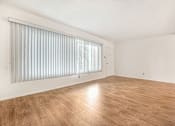 Thumbnail 1 of 9 - A room with wooden flooring and a window with blinds.