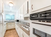 Thumbnail 3 of 9 - A modern kitchen with white cabinets and a black stove top oven.
