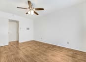 Thumbnail 6 of 9 - A room with a ceiling fan and wooden flooring.