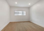 Thumbnail 6 of 11 - A room with wooden flooring and a window with blinds.