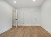 Thumbnail 7 of 11 - A room with two doors and wooden flooring.