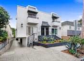 Thumbnail 9 of 11 - A white two-story house with a black gate and plants in front.