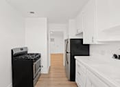 Thumbnail 3 of 11 - A black stove and refrigerator in a white kitchen.