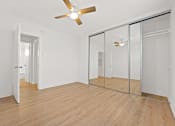 Thumbnail 6 of 11 - A room with a ceiling fan and mirrored doors.