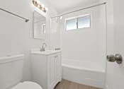 Thumbnail 7 of 11 - A white bathroom with a toilet, sink, and bathtub.