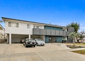 Thumbnail 1 of 3 - A modern two-story house with a garage and two cars parked in front.