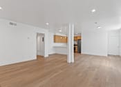 Thumbnail 2 of 12 - A spacious room with wooden flooring and white walls.