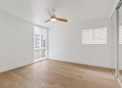 Thumbnail 5 of 12 - A room with a ceiling fan and wooden flooring.