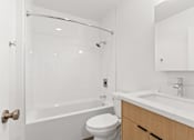 Thumbnail 9 of 12 - A white bathroom with a toilet, sink, and shower.