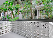 Thumbnail 4 of 35 - A white lattice fence with circular cutouts separates a patio from a lush green garden.