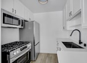 Thumbnail 12 of 35 - A kitchen with white cabinets and a black stove top oven.