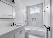 Thumbnail 18 of 35 - A white bathroom with a window above the bathtub.