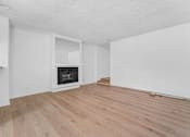 Thumbnail 3 of 12 - A room with a fireplace and wood flooring.