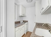 Thumbnail 4 of 12 - A kitchen with white cabinets and a granite countertop.