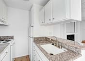 Thumbnail 5 of 12 - A kitchen with granite countertops and white cabinets.