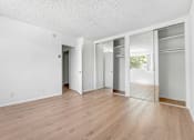 Thumbnail 7 of 12 - A room with white walls and wooden flooring with three doors.