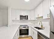 Thumbnail 47 of 56 - A modern kitchen with white cabinets and stainless steel appliances.