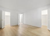 Thumbnail 50 of 56 - A room with white walls and wooden flooring with three open doors.