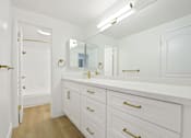 Thumbnail 51 of 56 - A white bathroom with a marble counter top and gold handles.