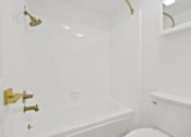 Thumbnail 52 of 56 - A white bathroom with a gold shower head and faucet.