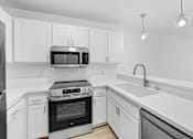 Thumbnail 14 of 56 - A modern kitchen with white cabinets and stainless steel appliances.