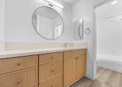 Thumbnail 18 of 56 - A bathroom with a vanity and a round mirror.