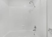 Thumbnail 19 of 56 - A white tiled shower with a shower head and faucet.