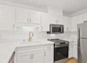 Thumbnail 34 of 56 - A kitchen with white cabinets and a black stove top oven.