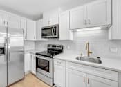 Thumbnail 4 of 56 - A modern kitchen with white cabinets and stainless steel appliances.