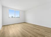Thumbnail 7 of 56 - Empty room with wooden flooring and a window.