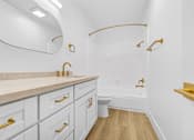 Thumbnail 10 of 56 - A white bathroom with gold fixtures and a marble counter.