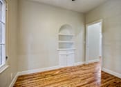 Thumbnail 6 of 16 - A room with a wooden floor and a white cabinet with shelves.