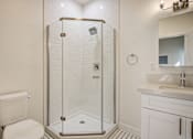 Thumbnail 7 of 16 - A white toilet sits next to a walk-in shower in a bathroom.